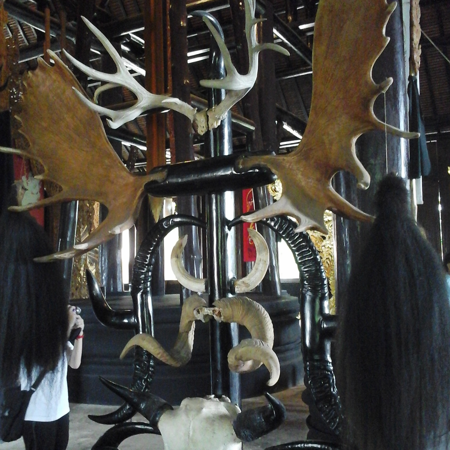 Huge wooden chairs made of antlers, horns, hair and skulls placed around a huge dining